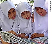 Thai Muslim students read headlines about the bloodless military coup in the newspapers in Thailand's restive southern Pattani province, 21 September 2006